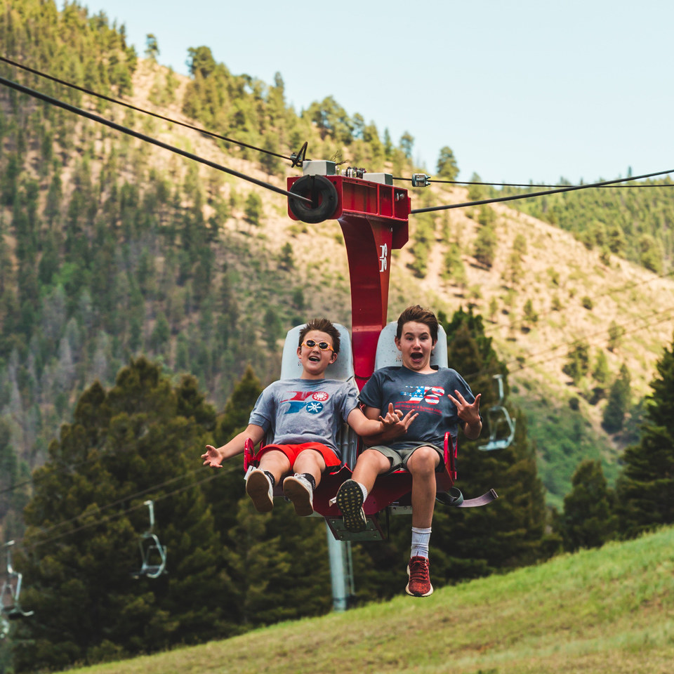two kids riding the pioneer flyer seated zip line